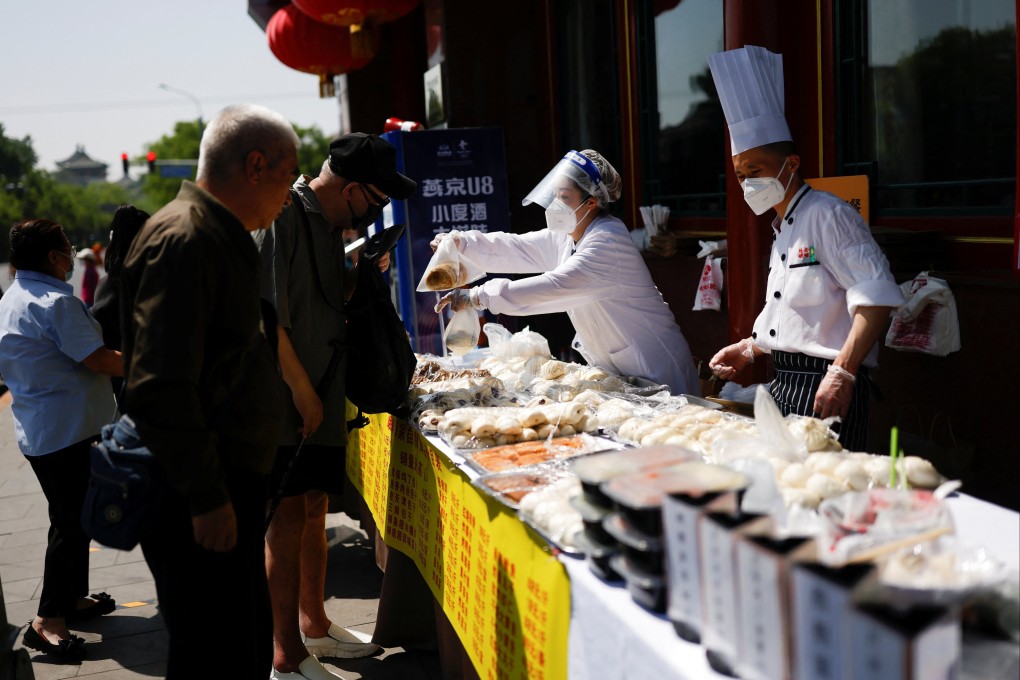 Workers wearing face masks sell food outside a restaurant, after the government banned dine-in services in Beijing. Photo: Reuters