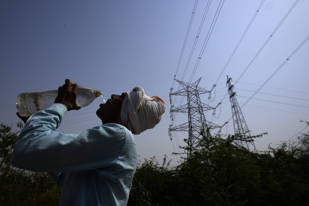 A workers quenches his thirst next to power lines as a heatwave continues to lashes the capital, in New Delhi, India on Monday, May 2, 2022. Photo: AP