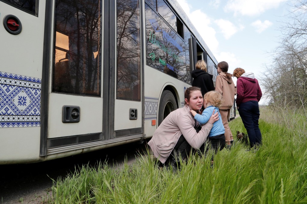 A woman holds a child next to a bus as civilians from Mariupol, including evacuees from Azovstal steel plant, travel in a convoy to Zaporizhzhia, during Ukraine-Russia conflict. Photo: Reuters