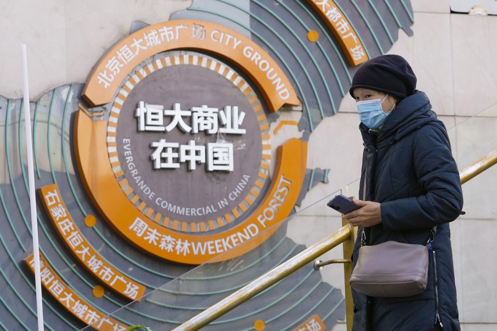 A woman passes by a display showing Evergrande’s China real estate projects in Beijing. Photo: AP Photo