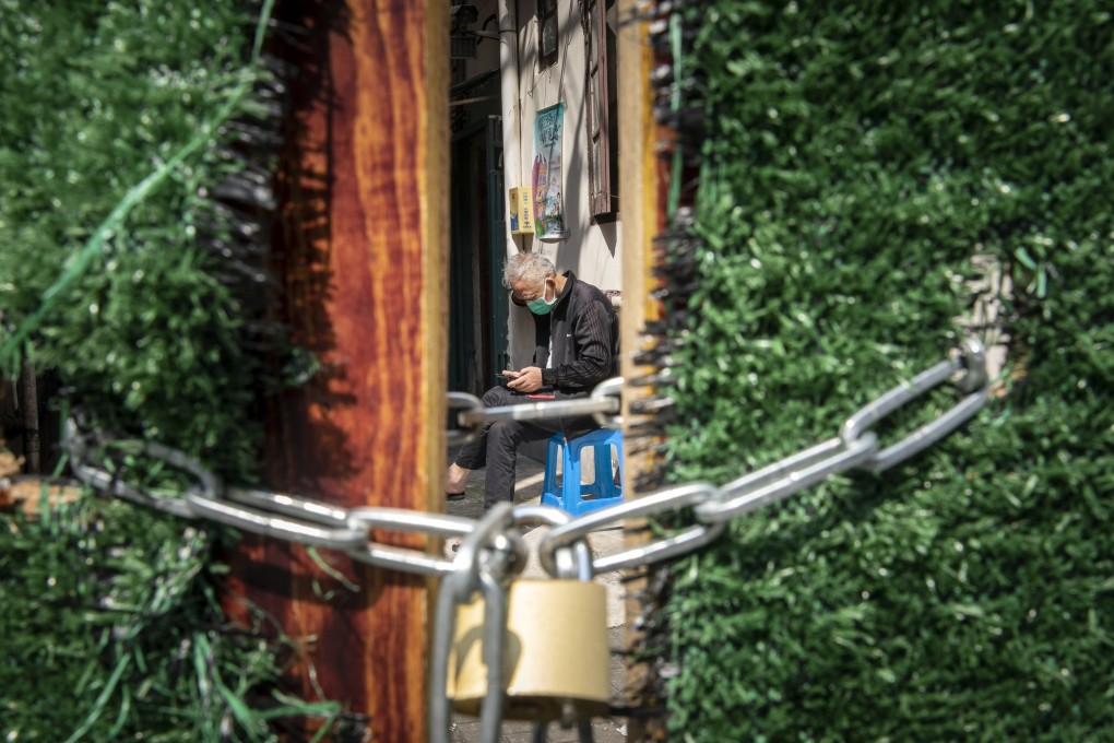 A resident sits behind a locked gate at a neighborhood during a lockdown due to Covid-19 in Shanghai on Tuesday, May 3, 2022. China’s financial and commercial hub had been under lockdown since April 1. Photo: Bloomberg