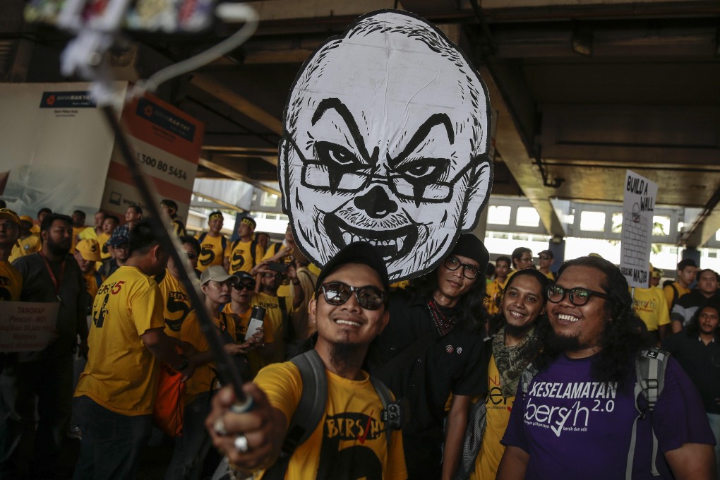 Malaysian anti-government protesters take a selfie with a placard bearing the likeness of then Prime Minister Najib Razak during a 2016 rally. Photo: EPA
