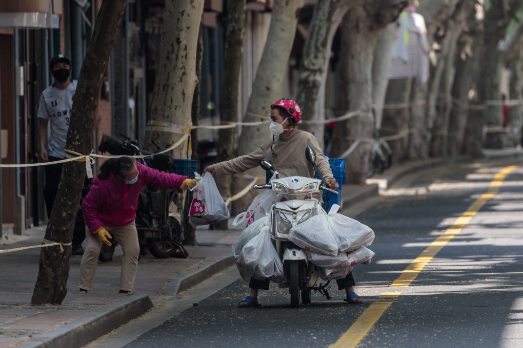 A delivery worker passes groceries to a woman on the street, amid a Covid-19 lockdown in Shanghai on May 2. Photo: EPA-EFE