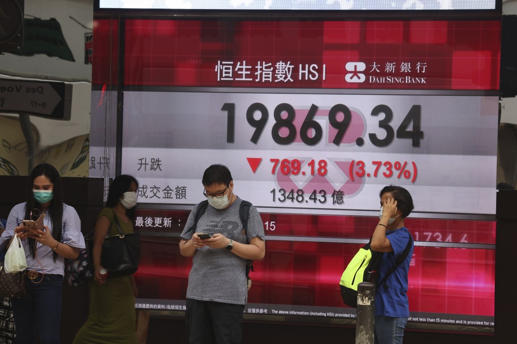 People passing by a screen showing the Hang Seng Index in Central, Hong Kong on April 15. Photo: K. Y. Cheng