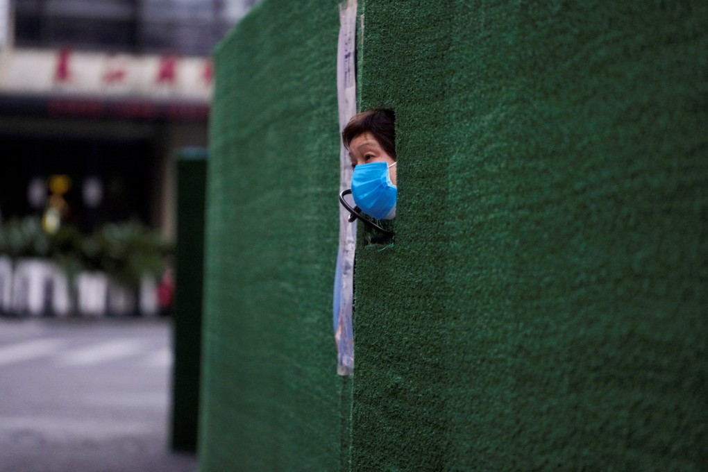 A woman looks out through a gap in the barrier at a residential area in Shanghai on May 6, 2022. The city remains under lockdown amid the latest Covid-19 outbreak. Photo: Reuters