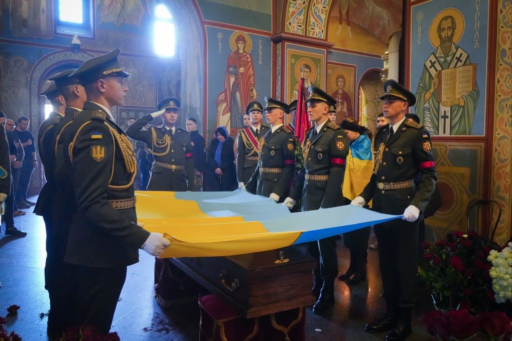 Soldiers place the Ukrainian flag on the coffin of volunteer soldier and journalist Oleksandr Makhov, killed by the Russian troops, at St Michael cathedral in Kyiv on Monday. Photo: AP