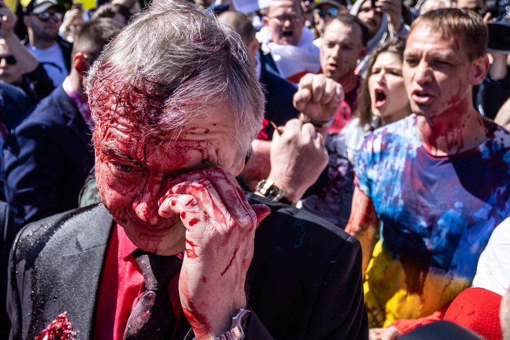 Russian Ambassador to Poland Sergey Andreev wipes his eye after being splattered with red paint by pro-Ukraine activists in Warsaw on Monday as he tries to lay a wreath to mark Victory Day. Photo: AFP