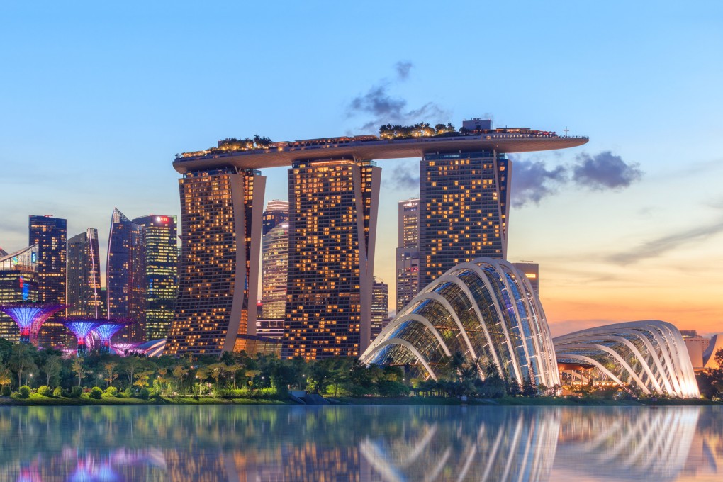 Marina Bay Sands hotel reflecting in water at dusk with glowing lights. Photo: Getty Images