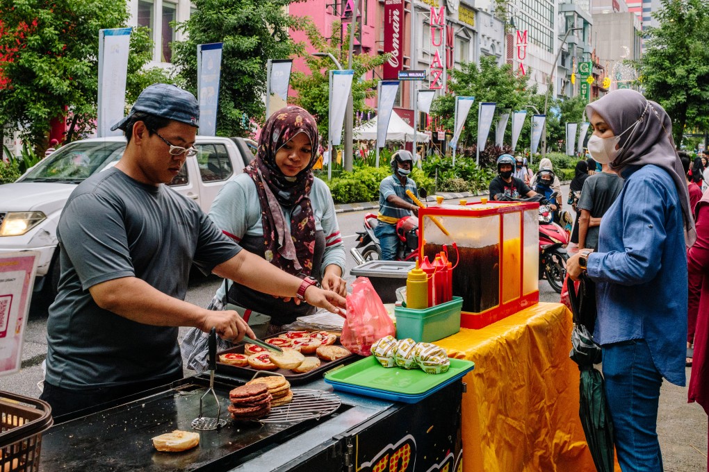 Food vendors serve a customer at a market in Kuala Lumpur, Malaysia. Malaysia’s economy grew at a faster-than-expected pace in the first quarter of the year as activity picked up with the easing of virus restrictions. Photo: Bloomberg
