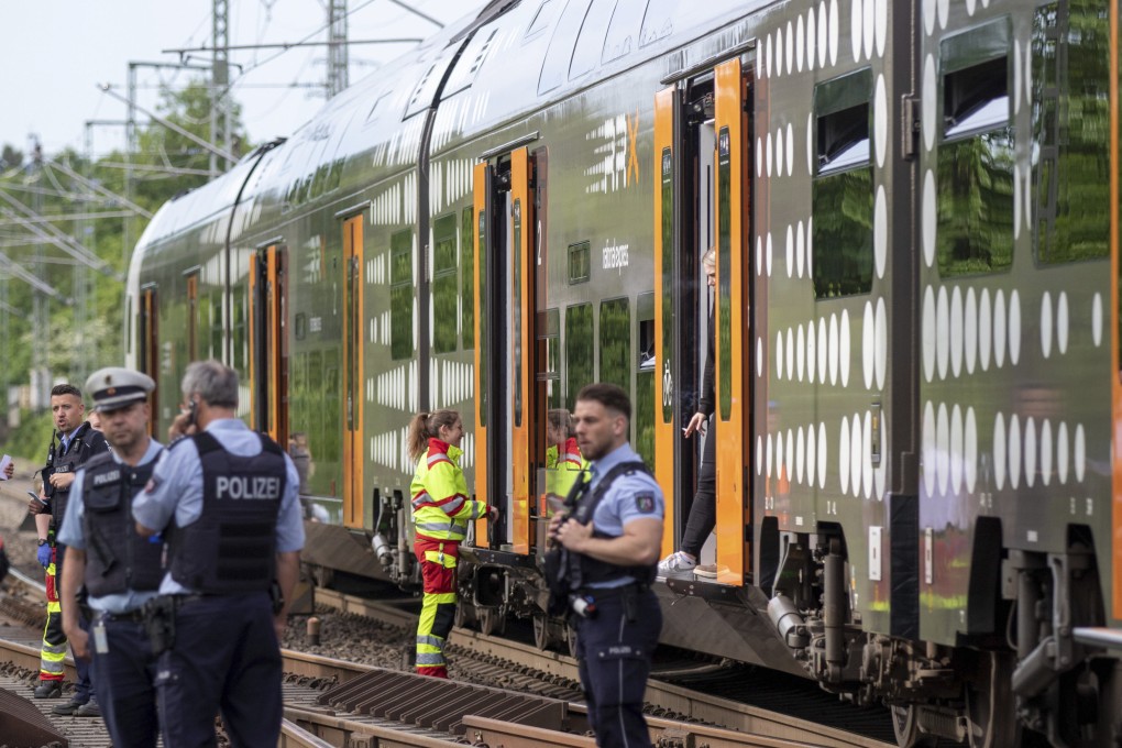 Police officers stand in front of a regional train in Herzogenrath, Germany on Friday. Three passengers on the train overpowered an Iraq-born man who wounded five people with a knife, authorities said. Photo: dpa via AP