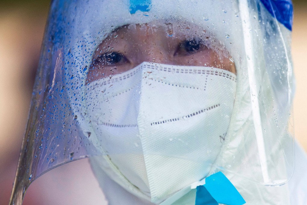 A community volunteer looks on while residents undergo nucleic acid tests for the Covid-19 coronavirus in a compound under lockdown in the Pudong district in Shanghai. Photo: AFP
