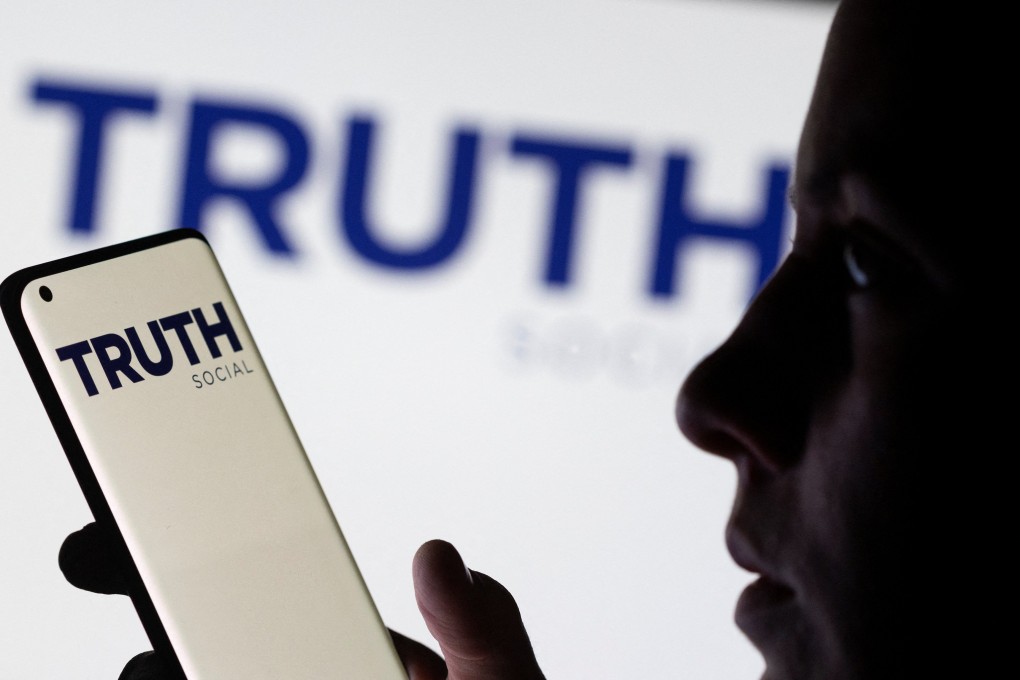 The Truth social network logo displayed behind a woman holding a smartphone in this picture illustration taken February 21. Photo: Reuters