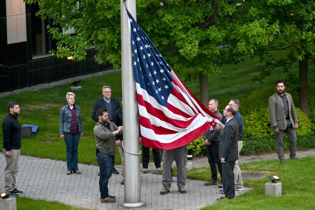Employees raise the stars and stripes on the flagpole outside the US embassy in Kyiv on Wednesday. Photo: AFP