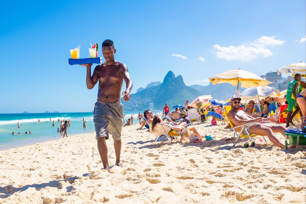 A Brazilian beach vendor carries a tray of home-made caipirinha cocktails on Ipanema Beach, Rio de Janeiro. Photo: Shutterstock