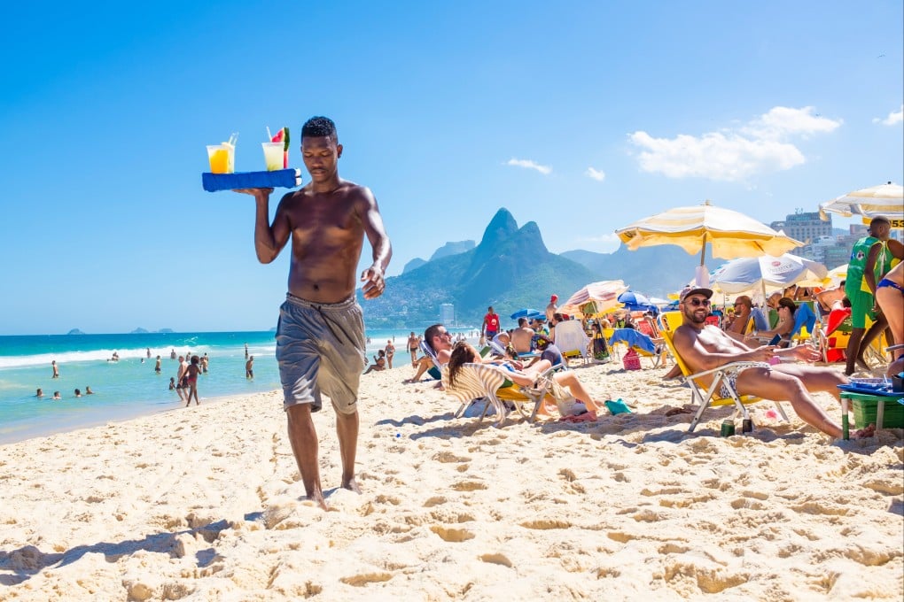A Brazilian beach vendor carries a tray of home-made caipirinha cocktails on Ipanema Beach, Rio de Janeiro. Photo: Shutterstock