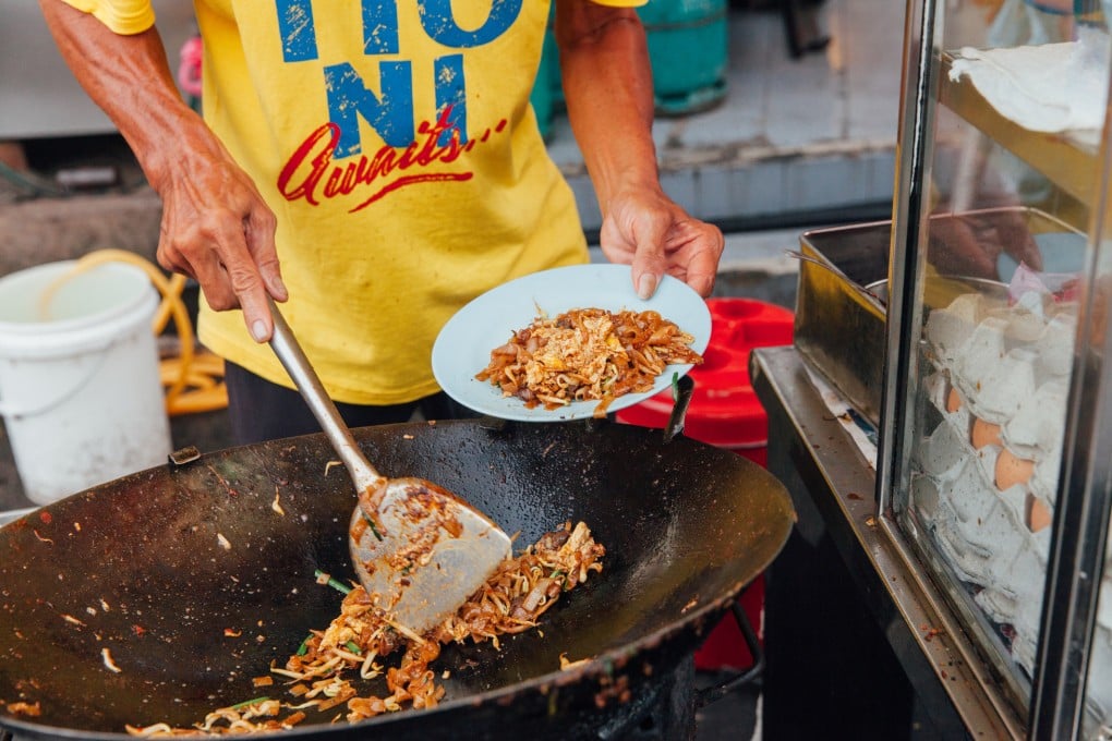A man cooks kway teow noodles at the Kimberly Street Food Night Market in George Town, Penang, Malaysia.