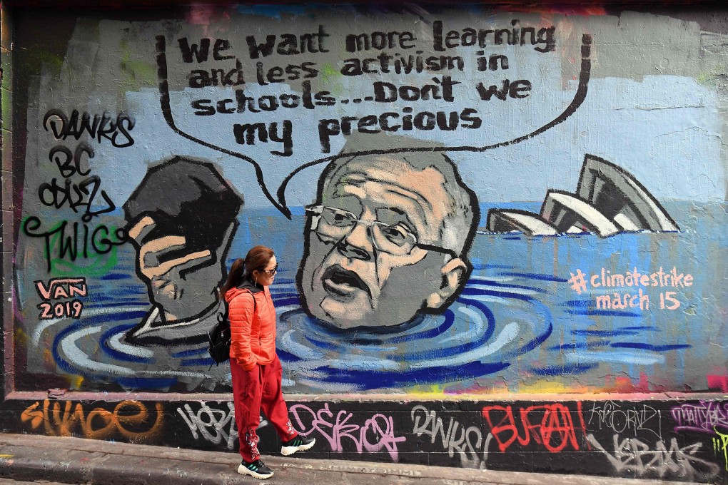 A tourist walks past a mural showing Australian Prime Minister Scott Morrison holding a lump of coal in Melbourne in 2019. Photo: AFP