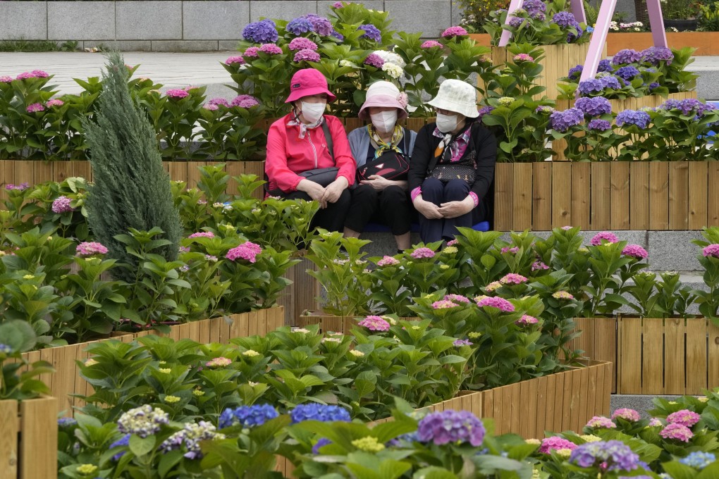 Women wearing face masks to help curb the spread of the coronavirus sit in a flower garden at a park in Goyang, South Korea, on April 28. Photo: AP