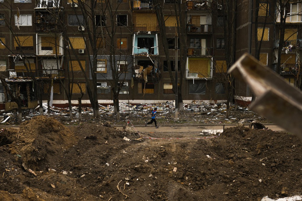 A jogger passes by a crater caused by a Russian strike opposite a block of flats in Kramatorsk, eastern Ukraine, on May 21. Photo: AP