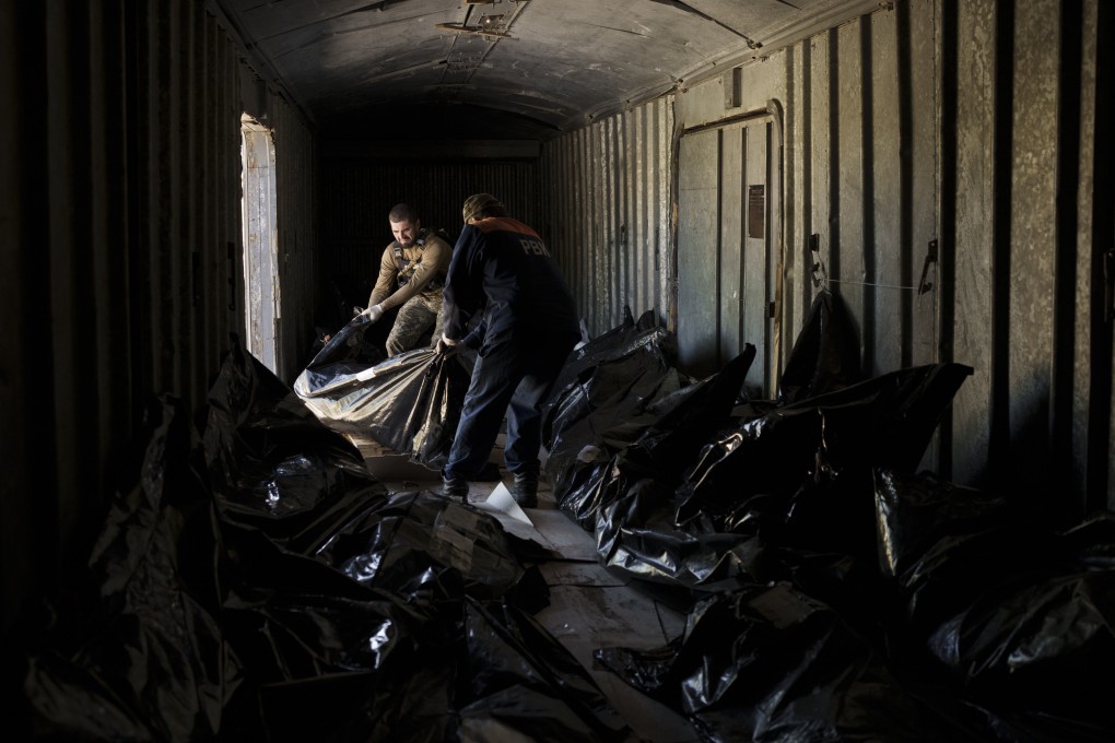 A Ukrainian serviceman and a worker carry the body of a Russian soldier into a refrigerated train in Kharkiv, Ukraine. Photo: AP