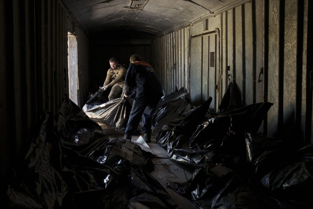 A Ukrainian serviceman and a worker carry the body of a Russian soldier into a refrigerated train in Kharkiv, Ukraine. Photo: AP