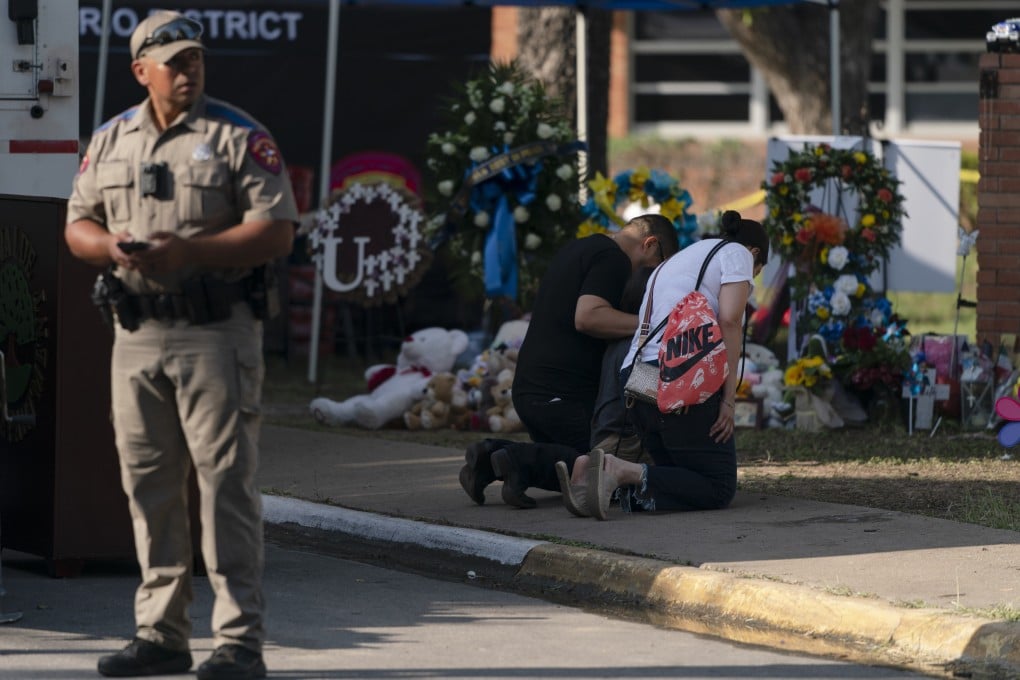 A family prays at a memorial as
a state trooper stands guard at Robb Elementary School in Uvalde, Texas, US on May 28. Photo: AP