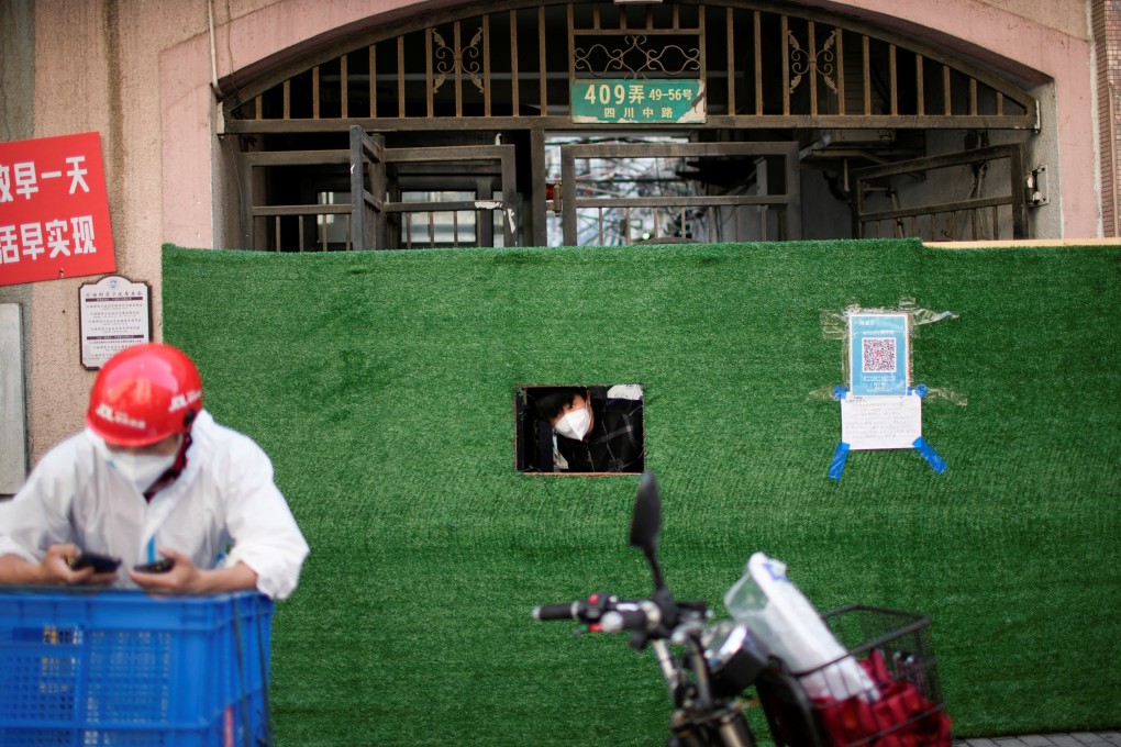 A resident looks out through a gap in the barrier in front of a residential area during lockdown in Shanghai on May 25. Photo: Reuters