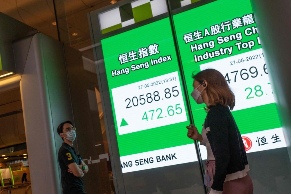 People walk past an electronic display showing the Hang Seng Index in Central, Hong Kong on May 27. Phoyo: AFP