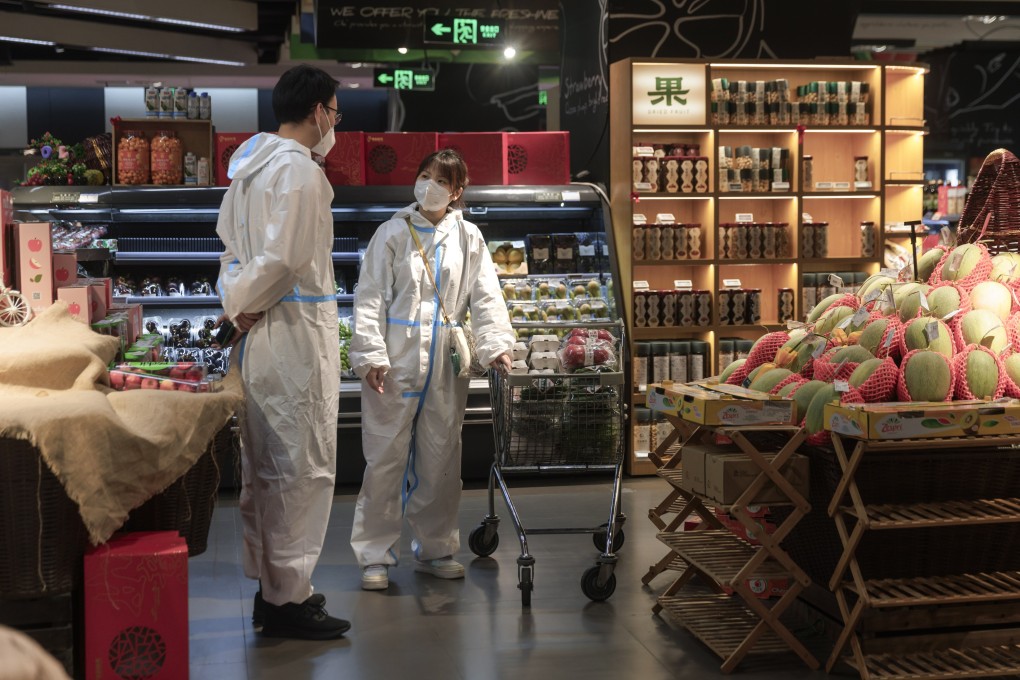 People in protective suits chat in a store in Shanghai on May 26. The effect of major city lockdowns in China has left its mark on consumer confidence, which fell sharply in March. Photo: EPA-EFE