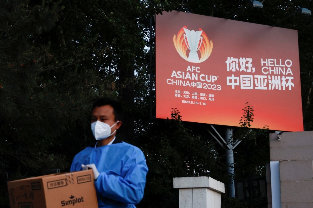 A man wearing personal protective equipment walks past a billboard of the AFC Asian Cup in Beijing on May 14. Photo: Reuters