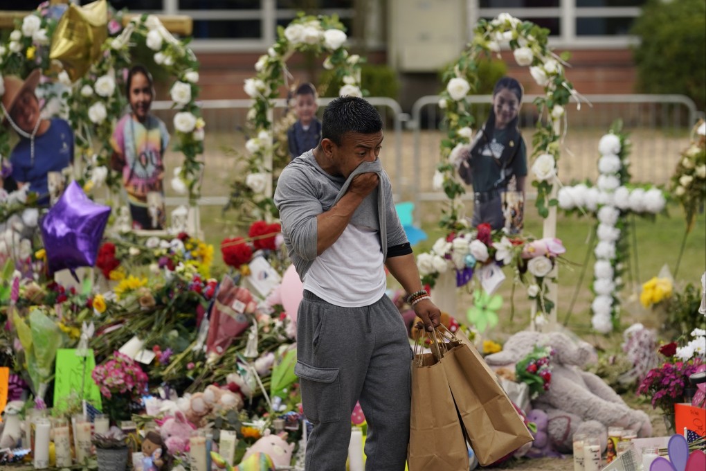 A man delivers flowers and candles to a memorial on Tuesday as he pays respects to the victims killed in a school shooting in Uvalde, Texas last week. Photo: AP