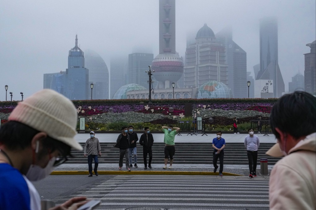 Residents cross the road near the bund as day breaks on Wednesday, in Shanghai, where authorities took major steps toward reopening China’s largest city after a two-month Covid-19 lockdown. Photo: AP