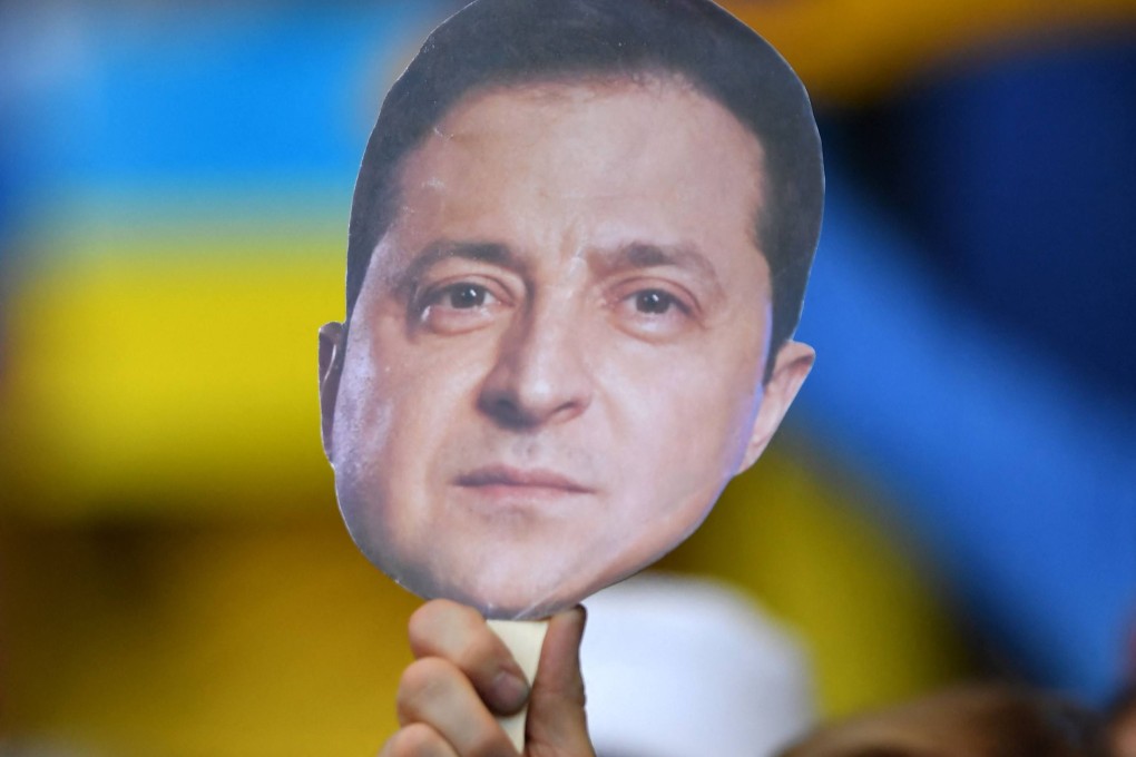 Football fans hold images of Ukraine’s President Zelensky during a football match between Scotland and Ukraine in Scotland on Wednesday. Photo: AFP
