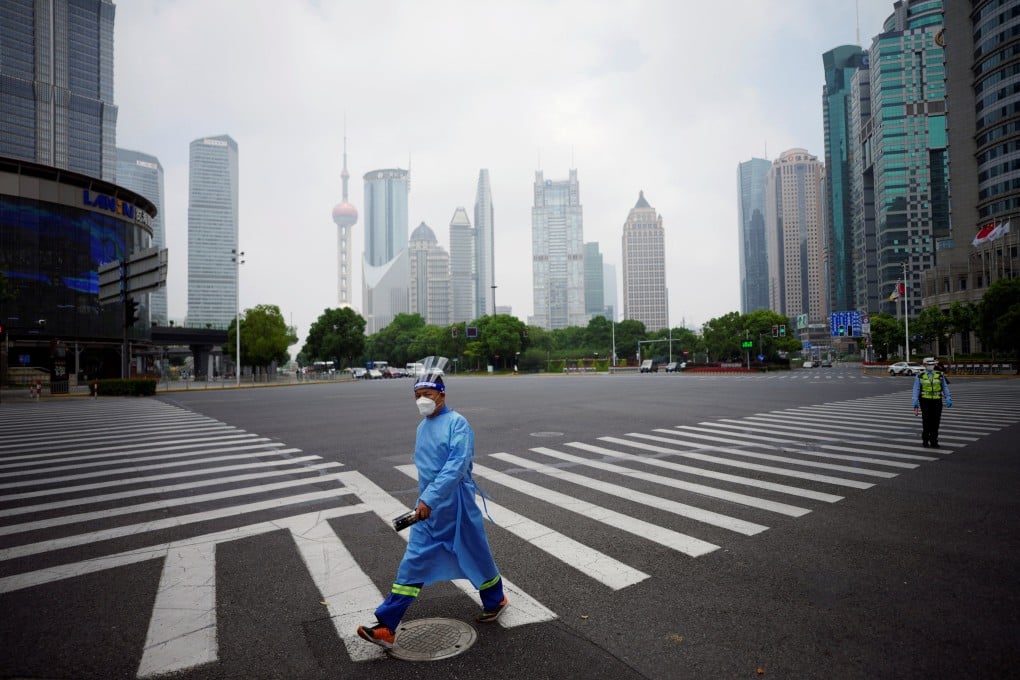 A worker in a protective suit walks on a pedestrian crossing at an intersection in Shanghai’s Lujiazui financial district on June 2, 2022. China’s rigid Covid-19 control measures have been driving reduced carbon emissions since March this year. Photo: Reuters
