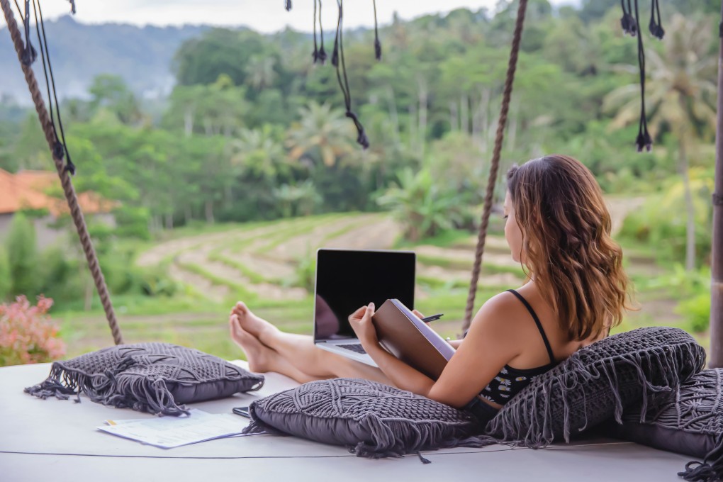 A young woman works remotely on the terrace of a holiday villa in Bali. Indonesia is offering five-year remote work visas to draw more such digital nomads for long stays. Photo: Getty Images