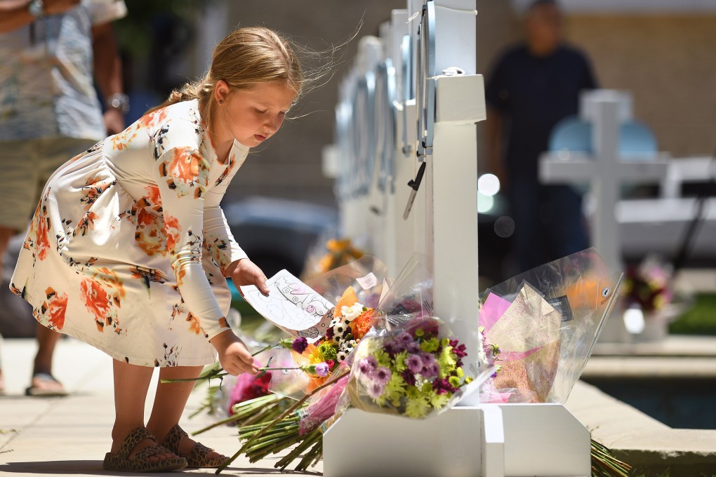 A child places flowers at a memorial for the victims of a mass shooting in Uvalde, Texas, on May 26. Nineteen students and two teachers died when a gunman opened fire in a classroom. Photo: Los Angeles Times/TNS