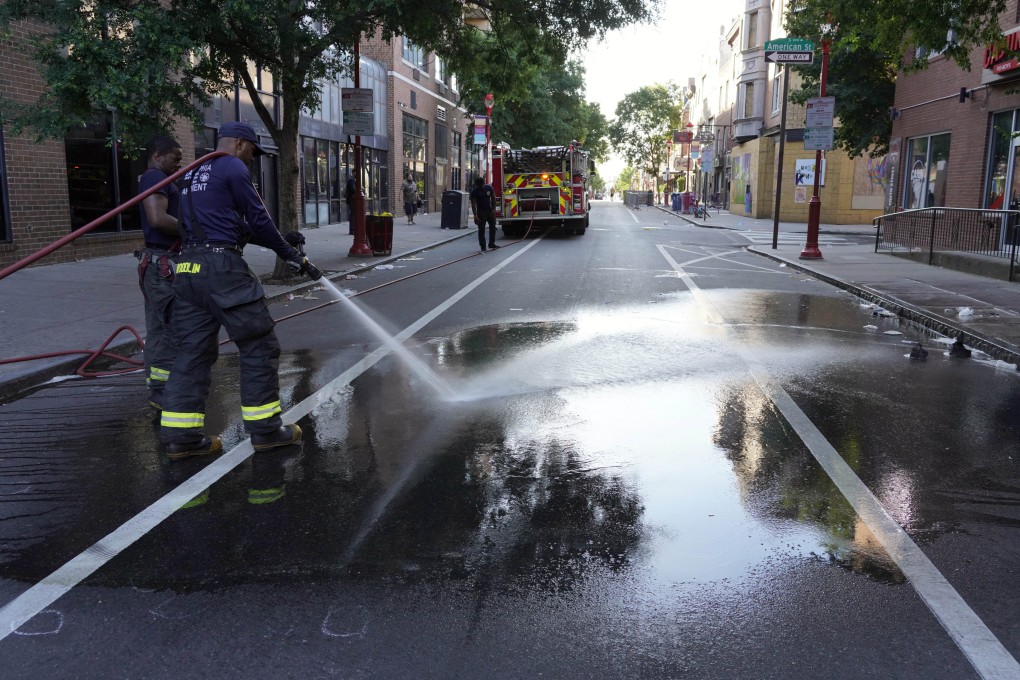 A Philadelphia firefighter washes blood off the road at the scene of a fatal shooting in Philadelphia on Sunday. Photo: AP