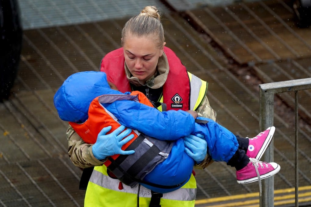 A UK military servicewoman carries a young child in the port of Dover in May, after the arrival of a group of people thought to be migrants following a small boat incident in the Channel. Photo: PA Wire via dpa