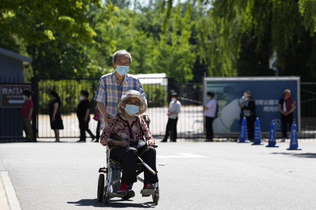 A man pushes an elderly woman past a line for Covid-19 testing on May 25 in Beijing. Photo: AP