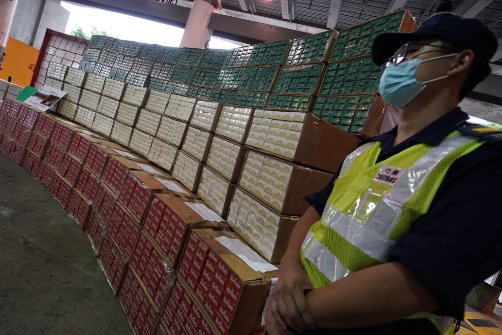 An officer stands next to boxes of illegal cigarettes worth HK$74 million seized by customs officers, during a press conference on May 10. Photo: Felix Wong