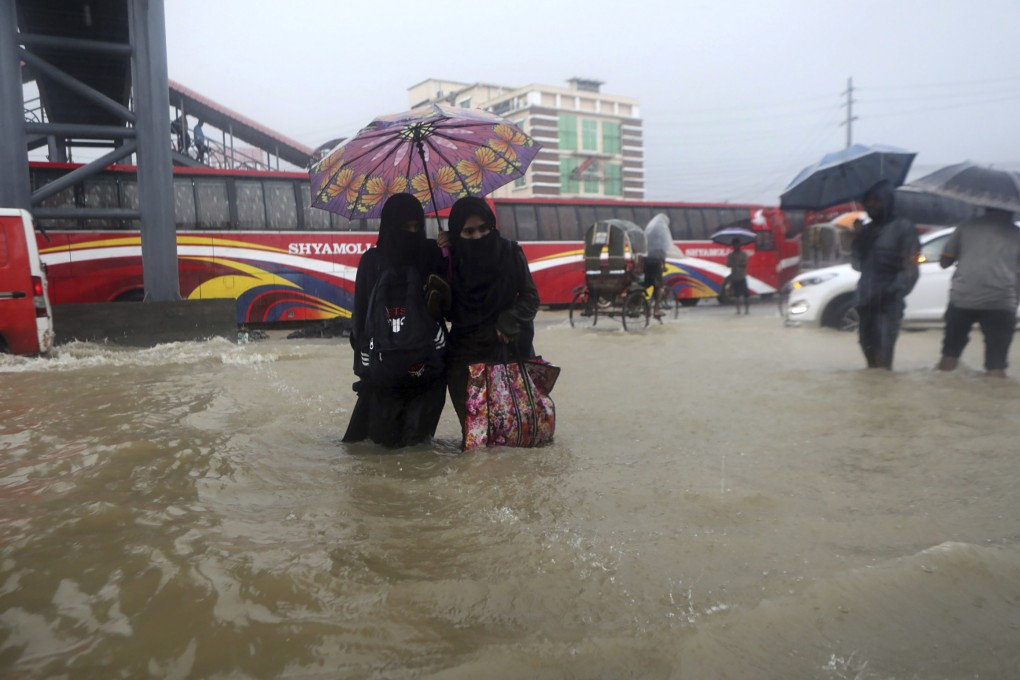 People wade through flood waters in Sylhet, Bangladesh, on Saturday, with millions of homes underwater. Rains are expected to continue over the weekend. Photo: AP