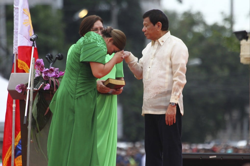 Philippine Vice President-elect Sara Duterte places the hands of her father, outgoing Philippine President Rodrigo Duterte, on her forehead as a sign of respect during her early swearing in ceremony on Sunday. Photo: AP