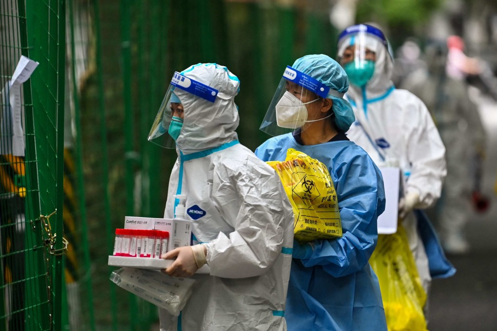Health workers carry swab samples taken from locked down residents in Shanghai. Photo: AFP