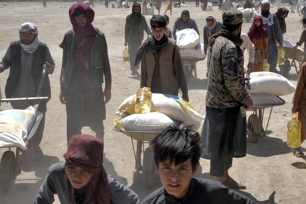 A Taliban fighter stands guard as people receive food rations in Kabul, Afghanistan, on April 30. US sanctions against the Taliban government have exacerbated a food crisis in Afghanistan. Photo: AP
