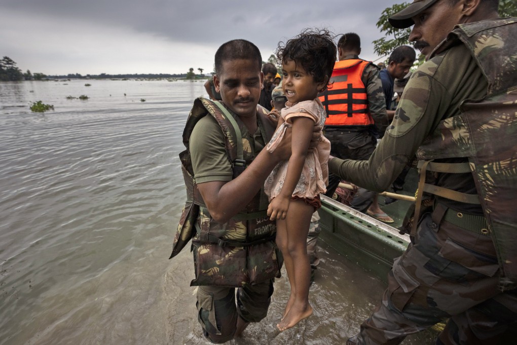 An Indian soldier carries a girl to a safer place after she and her family were rescued from a flooded village in the northeastern state of Assam. Photo: AP