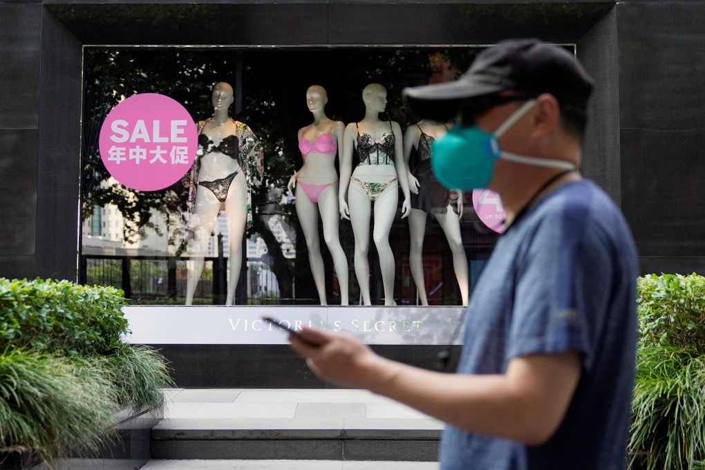 A man in Shanghai, wearing a face mask following the Omicron Covid-19  outbreak in spring, walks past a sale sign in the window of a Victoria’s Secret store. Photo: Reuters