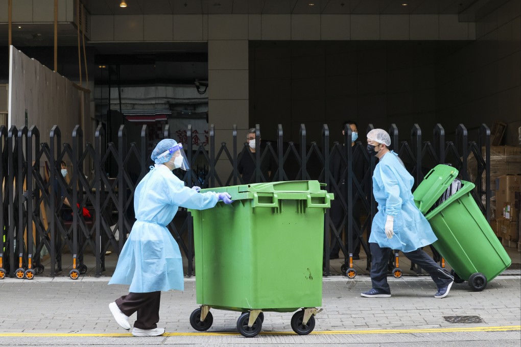 Workers in protective gear push garbage trolleys outside Courtyard by Marriott Hong Kong, a quarantine hotel, in Sai Ying Pun on April 26. Photo: Jelly Tse
