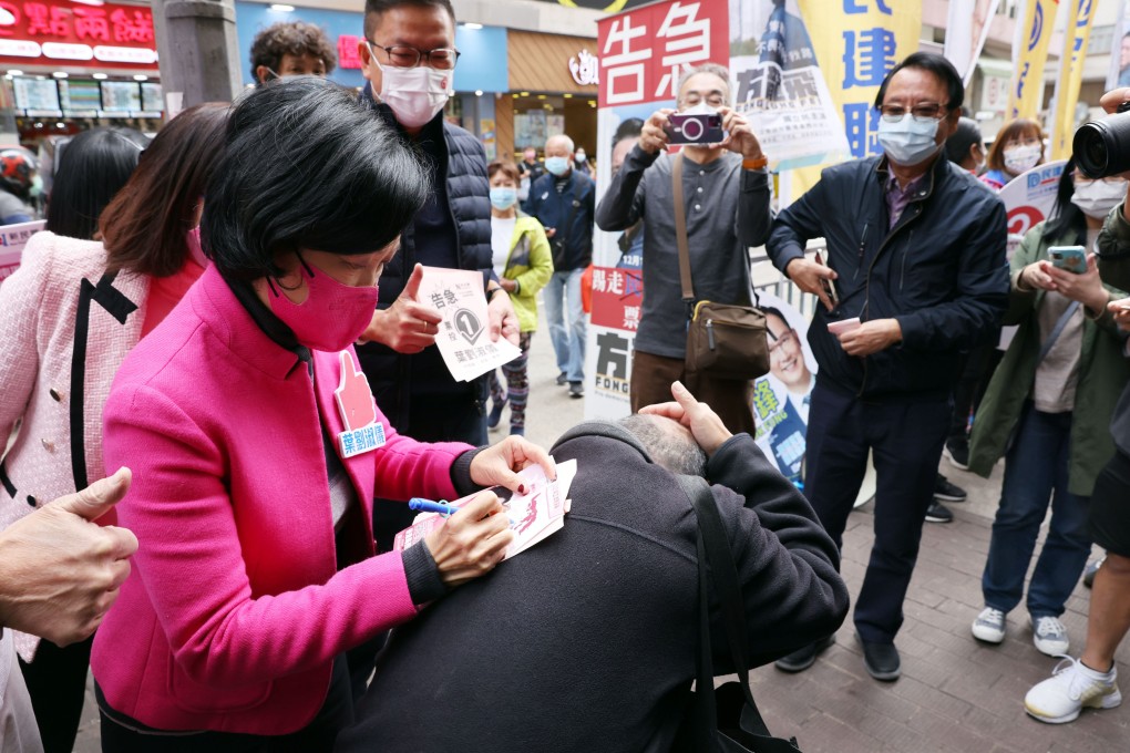 A supporter offers his back for Regina Ip Lau Suk-yee to sign an autograph for him as Ip calls for votes in Aberdeen at the Legislative Council General Election on December 19, 2021. Photo: Nora Tam