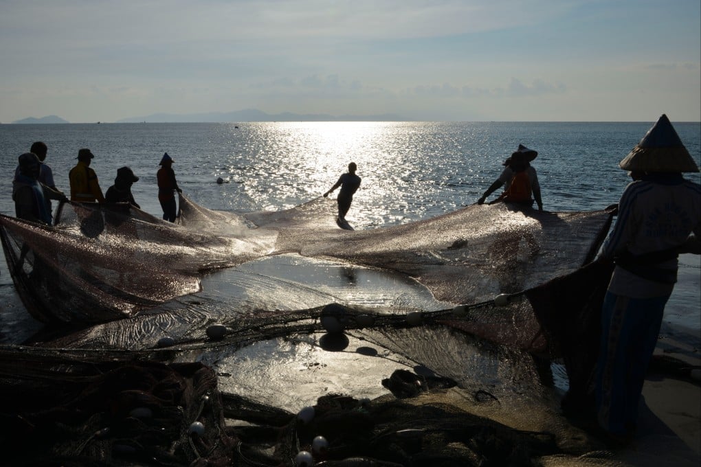 Fishermen carry their fishing nets along the shore in Banda Aceh in 2019. Photo: AFP