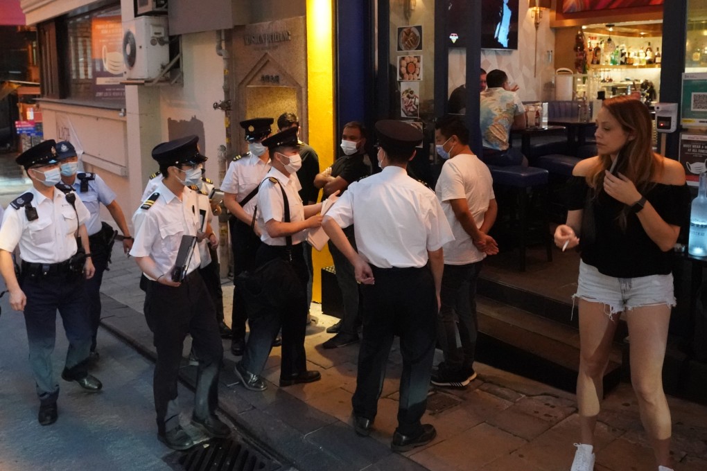Police officers and Food and Environmental Hygiene Department staff inspect bars in Lan Kwai Fong, Central. Premises have fallen foul of a new rule requiring bar patrons to show proof they have tested negative for  Covid-19 in the previous 24 hours. Photo: Felix Wong